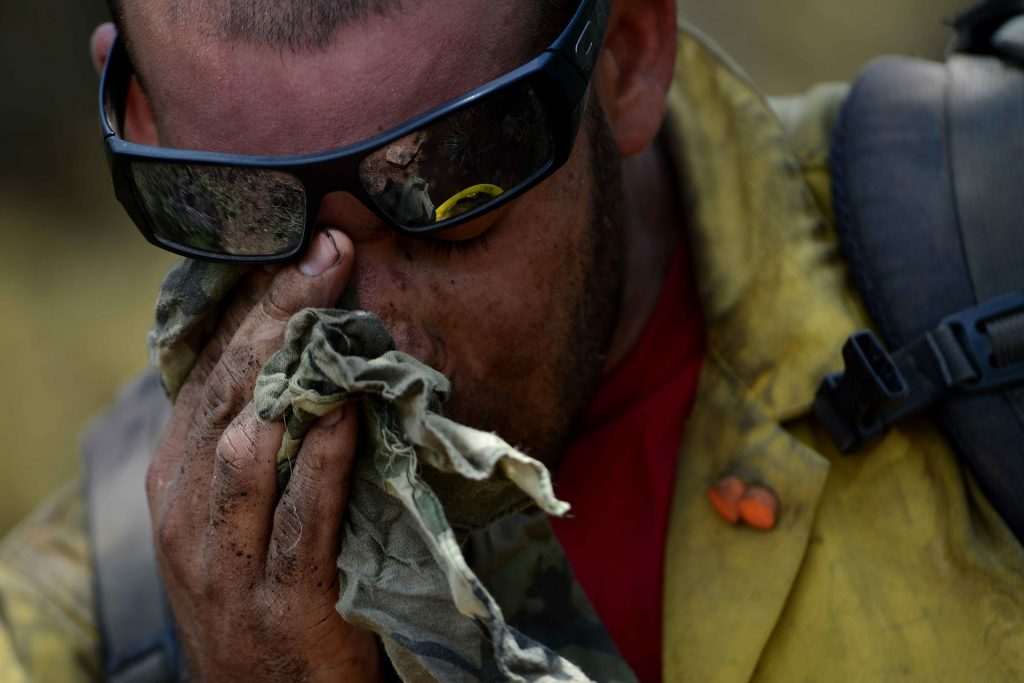 firefighter wiping sweat and soot away from his eye after fighting a fire