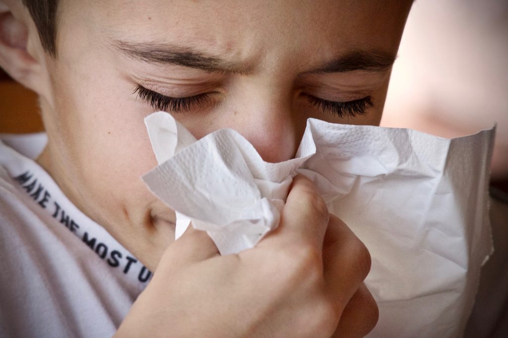 Young boy blowing nose into tissue