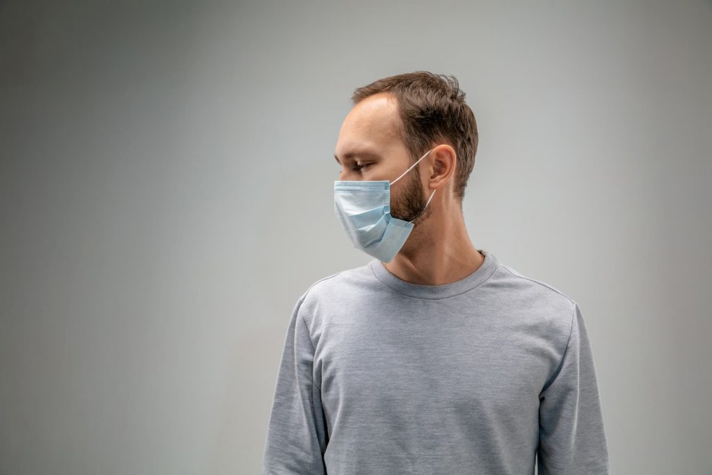 man wearing flu mask, gray shirt and background