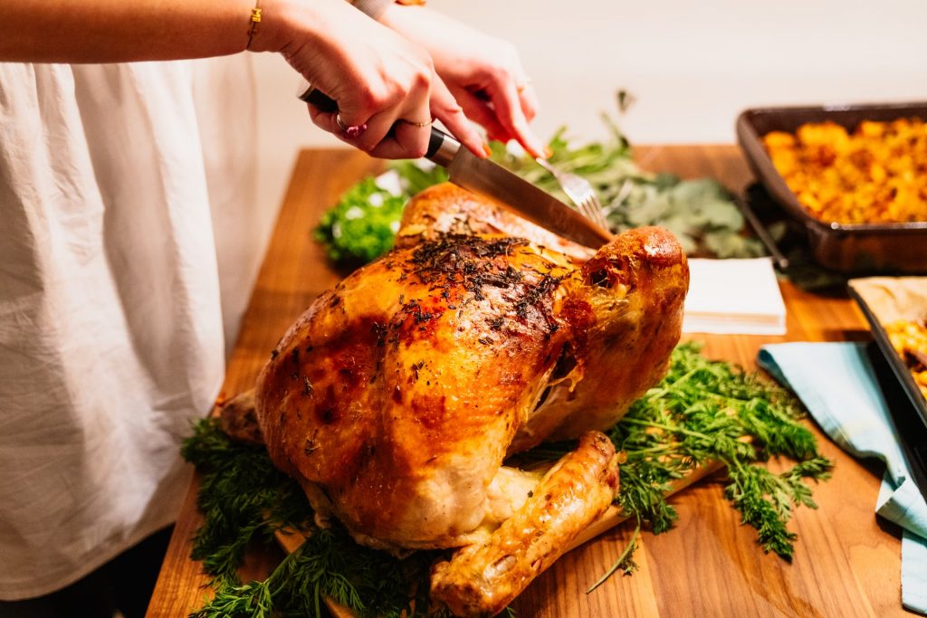 Woman carving turkey at Thanksgiving during COVID-19 pandemic