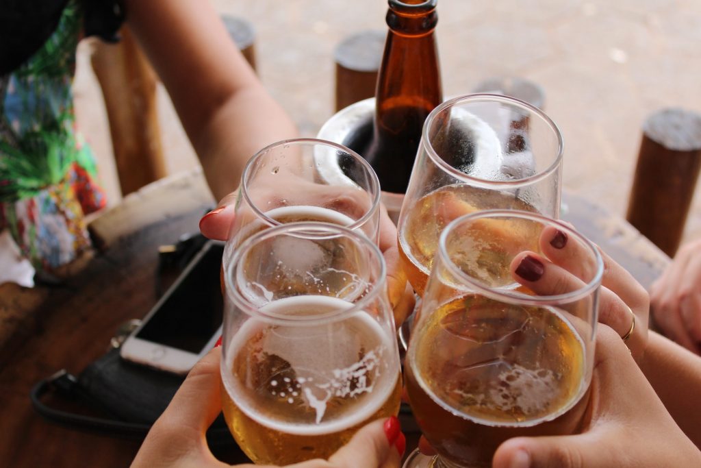 four girl friends getting together to drink alcohol wine and beer to celebrate - don't drink more than one alcoholic beverage to limit your risk of breast cancer