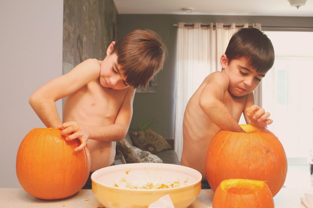Two kids carving pumpkins for Halloween; COVID-19 safety